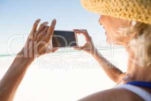 Close up of woman using smart phone while standing against sky
