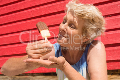 Senior woman eating ice cream while standing by hut