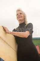 Low angle view of cheerful woman carrying surfboard