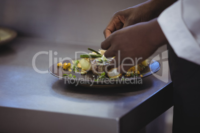 Close-up of chef garnishing meal on counter