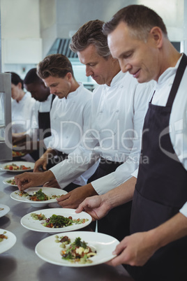 Team of chefs garnishing meal on counter