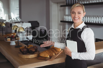 Portrait of smiling waitress standing at counter