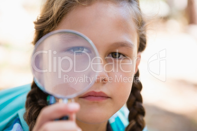 Girl looking through magnifying glass in the forest