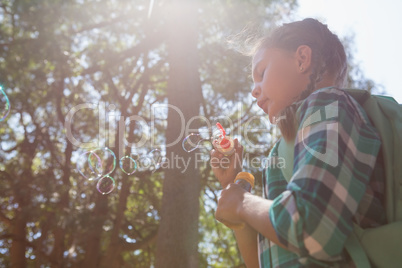 Girl blowing bubbles in the forest on a sunny day