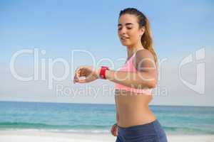 Young woman looking at smart watch while jogging at beach