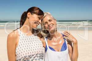 Happy mother and daughter standing on beach
