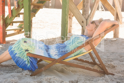 Side view of senior woman relaxing on chair against hut
