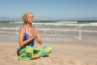 Close up of woman meditating while sitting on shore