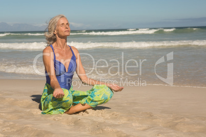Close up of senior woman meditating while sitting on shore