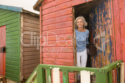 Portrait of smiling senior woman standing at beach hut
