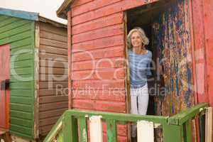 Portrait of smiling senior woman standing at beach hut