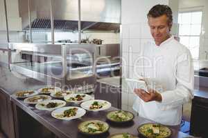 Male chef using digital tablet at order station