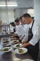 Team of chefs garnishing meal on counter