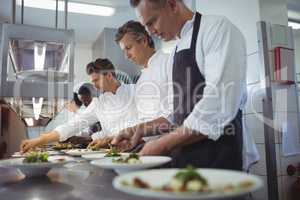 Team of chefs garnishing meal on counter