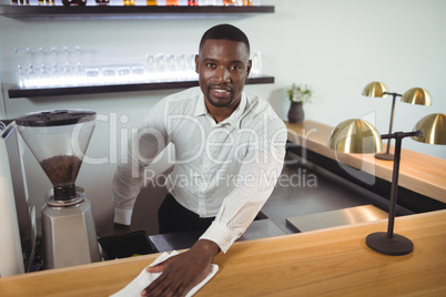 Bar tender cleaning bar counter in restaurant