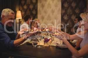 Man passing a meal plate to woman at table