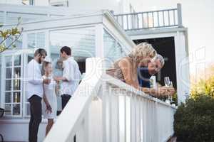 Friends interacting while having champagne in balcony