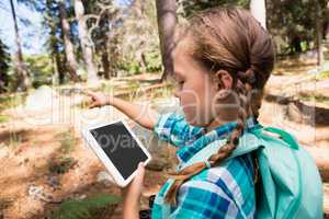 Girl pointing while using digital tablet in the forest