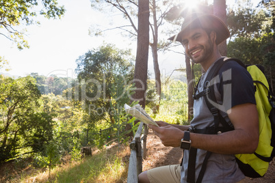 Smiling man holding the map and standing near the fence