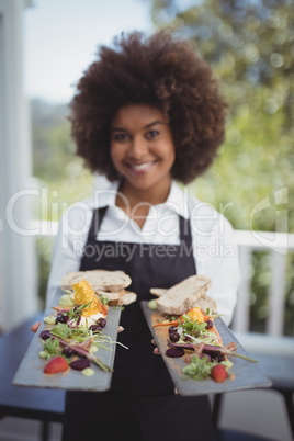 Portrait of smiling waitress holding food tray