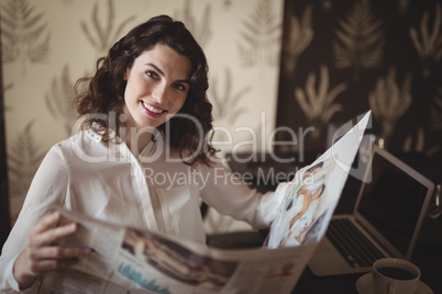 Beautiful woman reading newspaper in restaurant