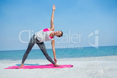 Full length of woman exercising on mat at beach