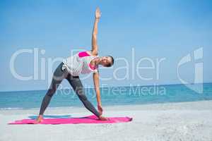 Full length of woman exercising on mat at beach
