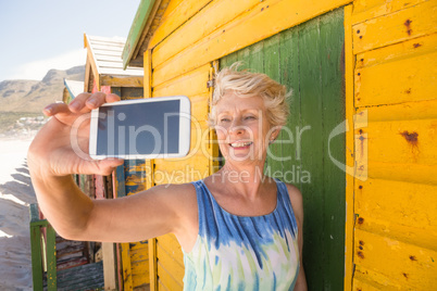 Senior woman taking selfie while standing against hut