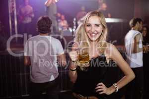 Portrait of smiling woman holding beer mug at nightclub