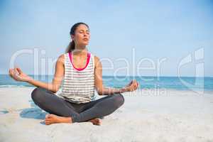 Full length of young woman with eyes closed meditating at beach