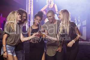 Happy friends toasting beer glasses with performer singing in background