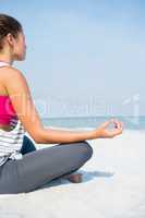 Full length of young woman meditating on sand at beach