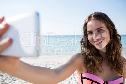 Happy young woman wearing bikini while taking selfie at beach