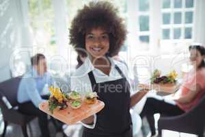 Portrait of smiling waitress holding food tray