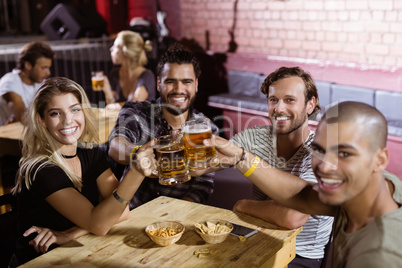 Portrait of happy friends toasting beer mugs at nightclub