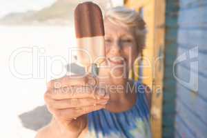 Close up of senior woman holding ice cream while standing by hut