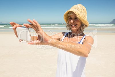 Smiling woman using smart phone while standing at beach