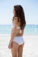 Side view of woman in bikini standing at beach