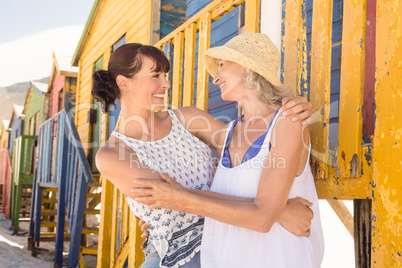Happy mother and daughter embracing while standing against wall