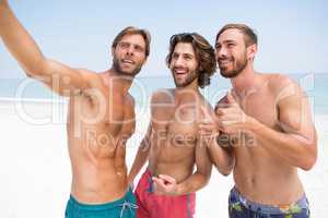 Smiling male friends standing at beach