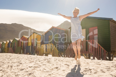 Happy woman jumping on sand against huts
