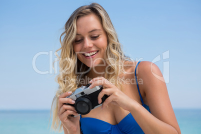Woman photographing while standing against clear sky