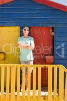 Senior man with arms crossed standing by railing of beach hut