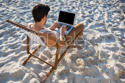 High angle view of man using laptop at beach