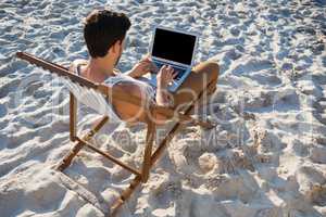 High angle view of man using laptop at beach