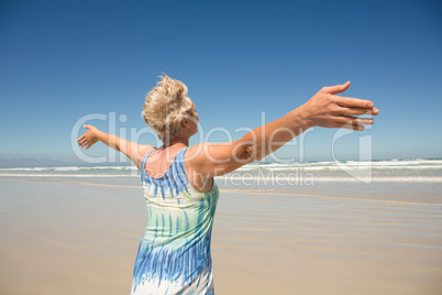 Rear view of woman with arms outstretched standing against clear sky
