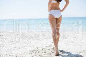 Low section of woman with hand on hip at beach