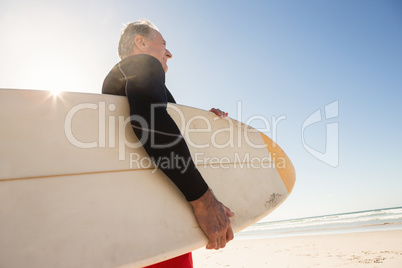 Low angle view of man carrying surboard while standing at beach