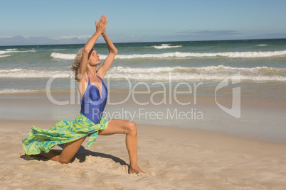 Full length of senior woman with arms raised on sand