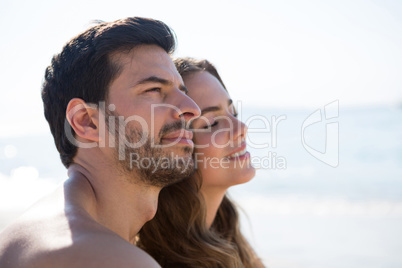 Side view of thoughtful couple sitting at beach